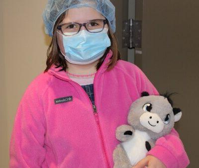 child wearing surgical mask 和 cap 和 holding stuffed animal